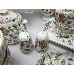Minton Haddon Hall pattern tea and dinner wares, including basket dish, two covered tureens, six dinner plates, eight dessert plates, twelve tea plates, six soup bowls, six cereal bowls, teapot, coffee pot, milk jug, covered sucrier twelve tea cups and saucers, six mugs, footed bon bon dish, pair of candlestick holders, cake knife and slice etc (81)