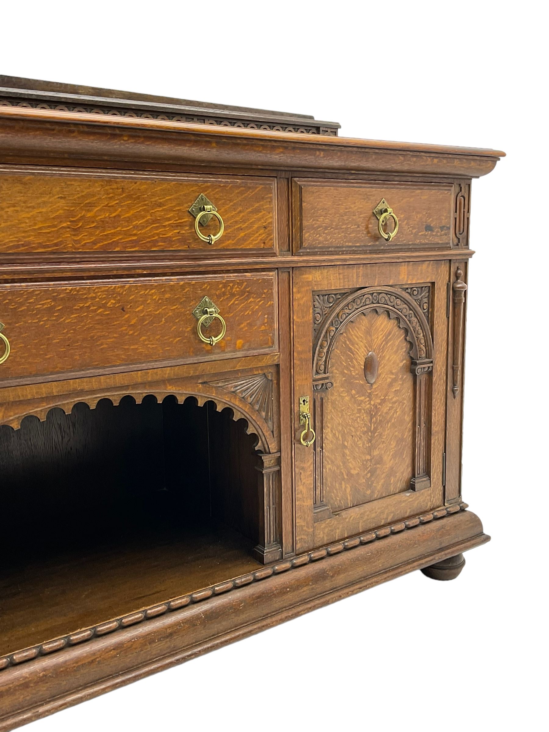 Edwardian oak sideboard, raised arcade carved back over rectangular top, fitted with four drawers, two arch carved doors doors flanking open arched centre, on turned feet