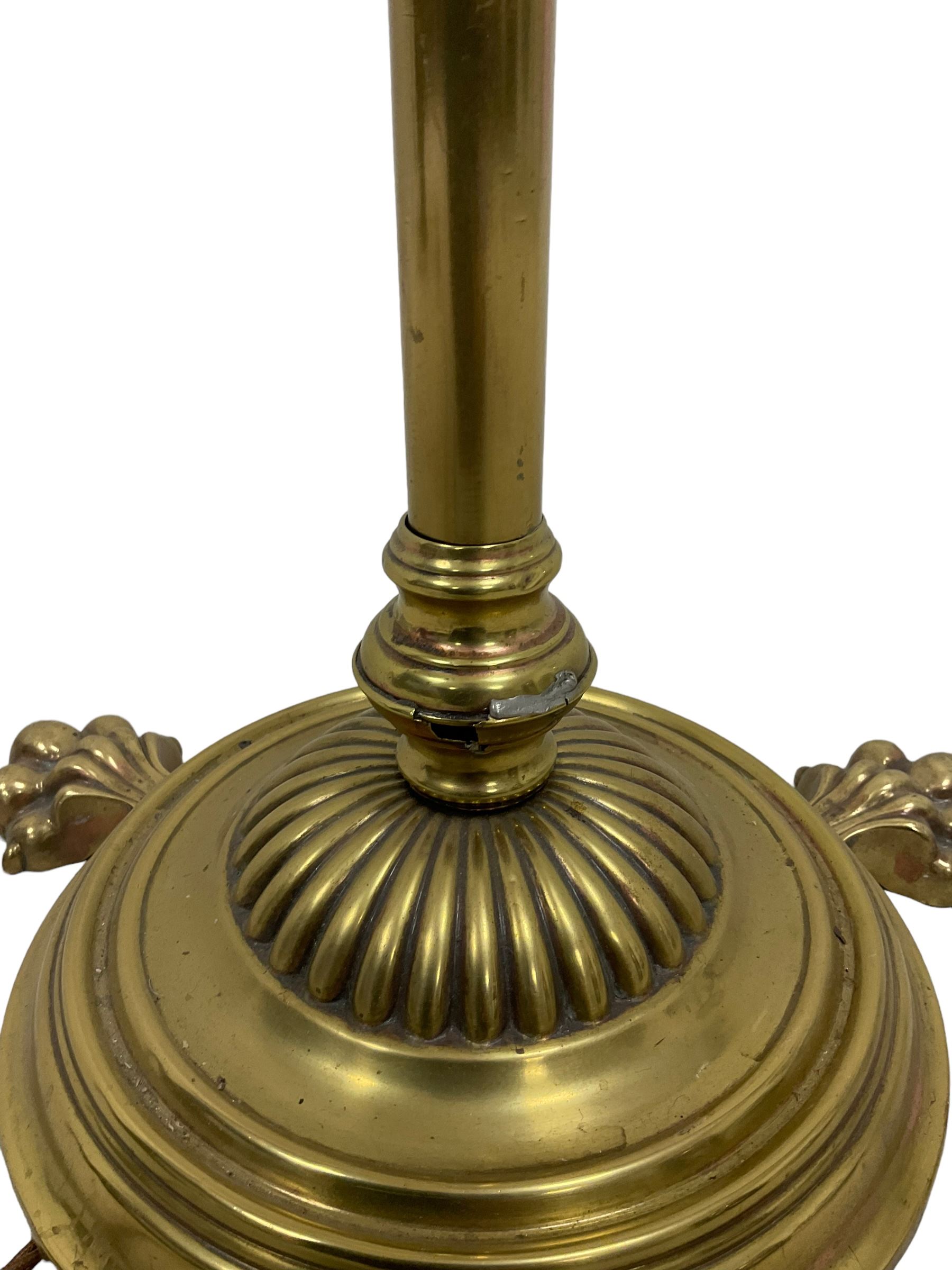 Edwardian brass plated copper standard lamp, telescopic stem on lobe moulded circular base with three projecting paw feet, with cream shade