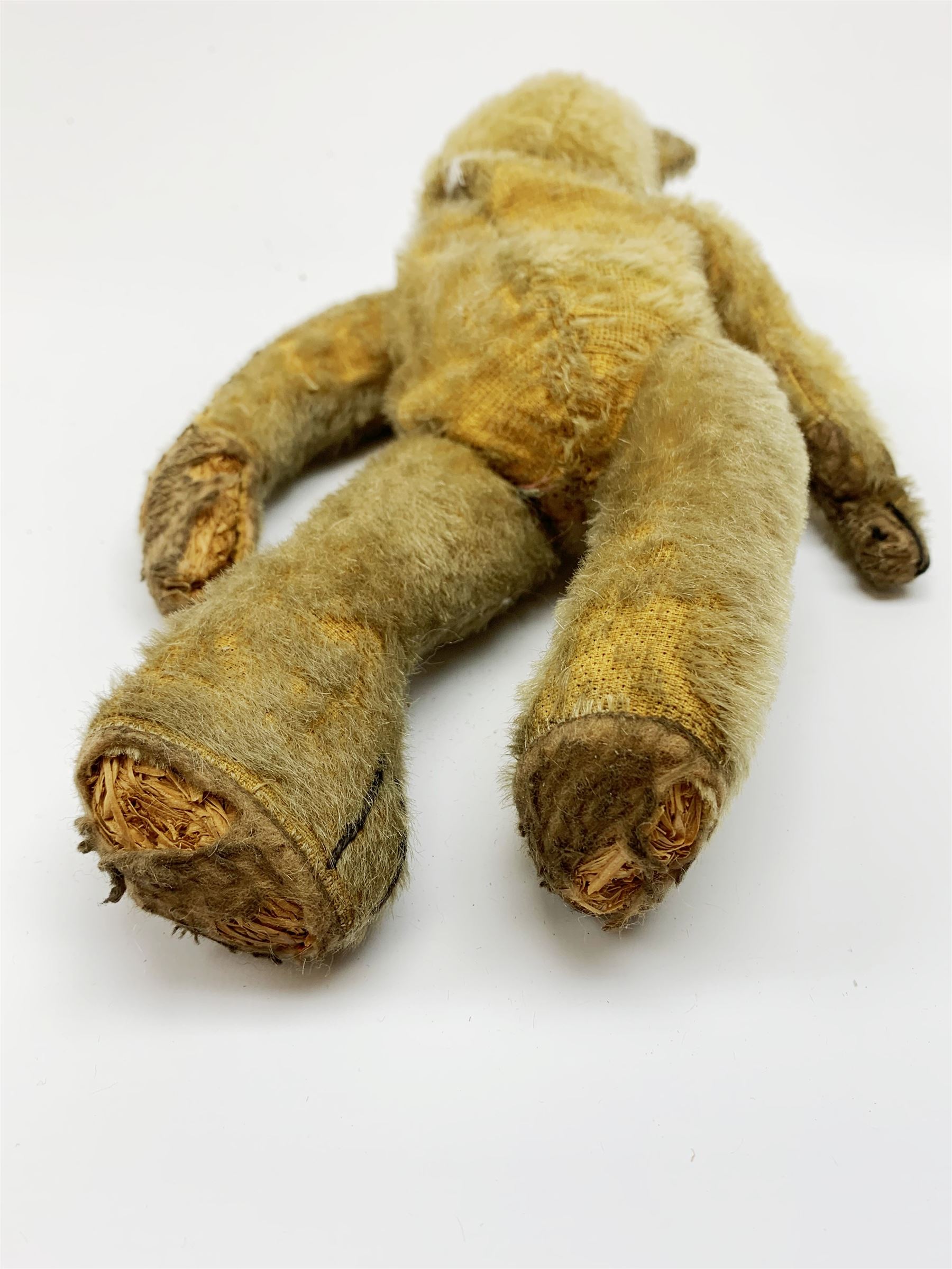 Early 20th century American mohair teddy bear c1920 with wood wool filled body humped back body with jointed limbs, black boot button eyes and horizontal stitched nose and mouth H12