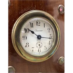 1920's-Aviation clock, mahogany case configured from part of an early 20th century aeroplane propellor, mounted on a conforming plinth with a shaped base, bolt holes filled with brass studs and fitted with an 8-day American spring driven Ansonia insertion movement with a porcelain dial, Arabic numerals, spade hands and seconds dial. Wound and set from the rear.