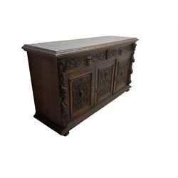 Victorian heavily carved oak sideboard, the moulded top carved with foliate decoration to the edge, fitted with two drawers and three cupboards, the drawer fronts carved with green man mask handles and scrolling foliage, the panelled doors carved with interlacing foliage, on turned compressed bun feet