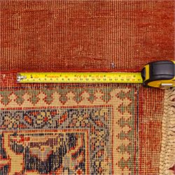 North West Persian Tabriz hand-knotted carpet, salmon field with central elongated lozenge medallion intricately filled with scrolling arabesques and palmettes, framed by stylized corner spandrels within a broad indigo main border  of bold palmettes and floral vinery between multiple guard stripes, rendered in tones of terracotta, sage green, and soft ivory, with cotton fringe ends 