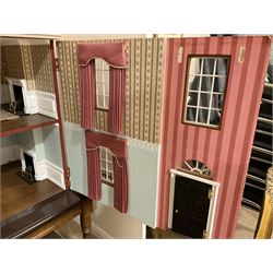 Good quality late 20th century wooden dolls house by M. James dated 1992, as a 19th century style three-storey double fronted property with textured brick walls and faux slated pitched roof with dormer windows, the double hinged front elevation with faux iron railings, opening to reveal four rooms on two floors with central hall stairs and landing; the roof hinged along the ridge opening to give access to two further rooms with central bathroom; windows to both front and rear elevations with drapes; simulated floor boards and tiling throughout with decorated walls, coving and ceilings; wired for electric lighting with bank of switches on the back; bears makers plaque W92cm H89cm D47cm; on modern oak two-tier coffee table as stand.
Auctioneers Note: the WC cistern is no longer fitted in the bathroom and is not included with this lot.