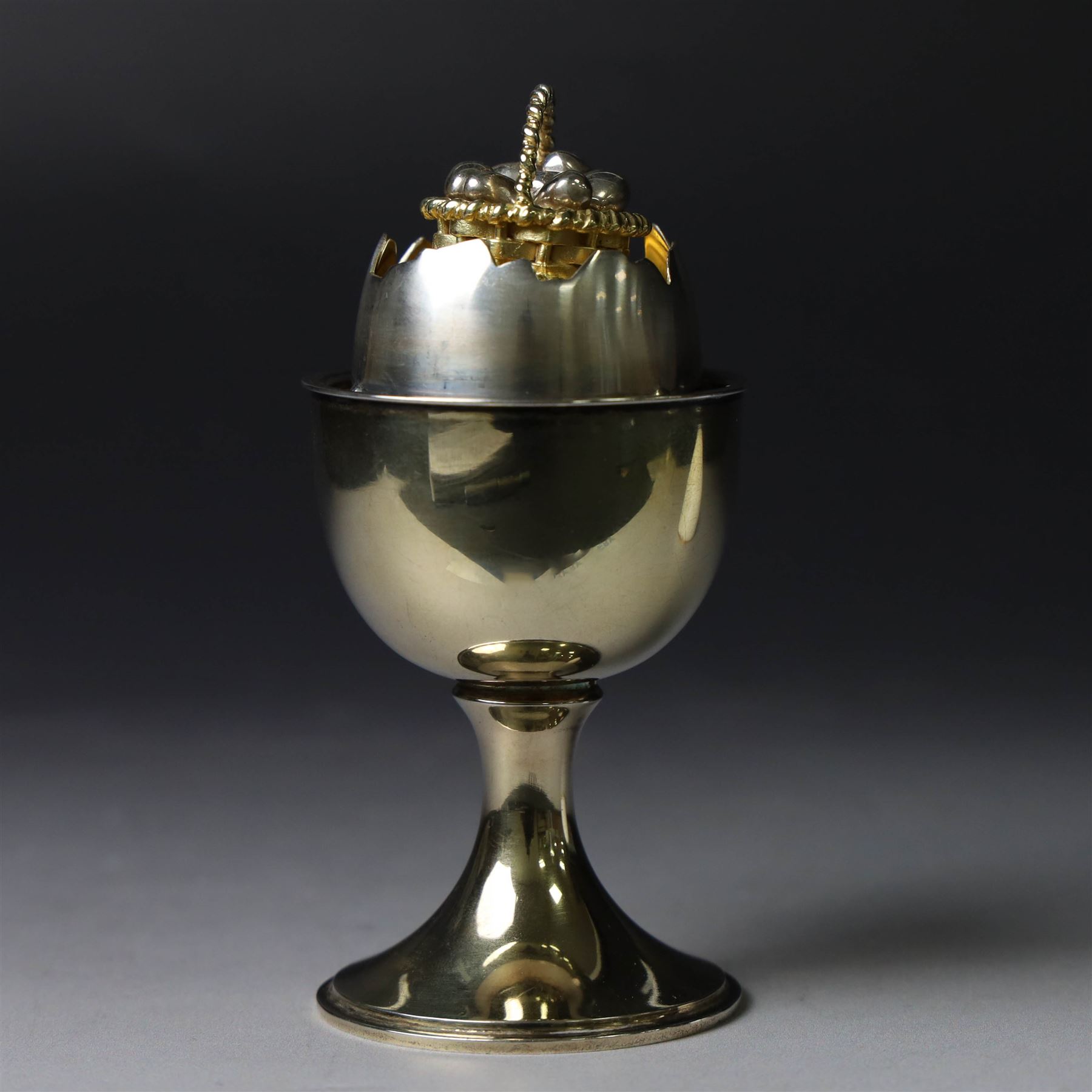Late 20th century silver-gilt novelty surprise egg by Anthony Gordon Elson, the egg cup containing a  removeable shell, lifting to reveal a parcel gilt egg basket beneath, hallmarked Anthony Gordon Elson, London 1979, H11cm