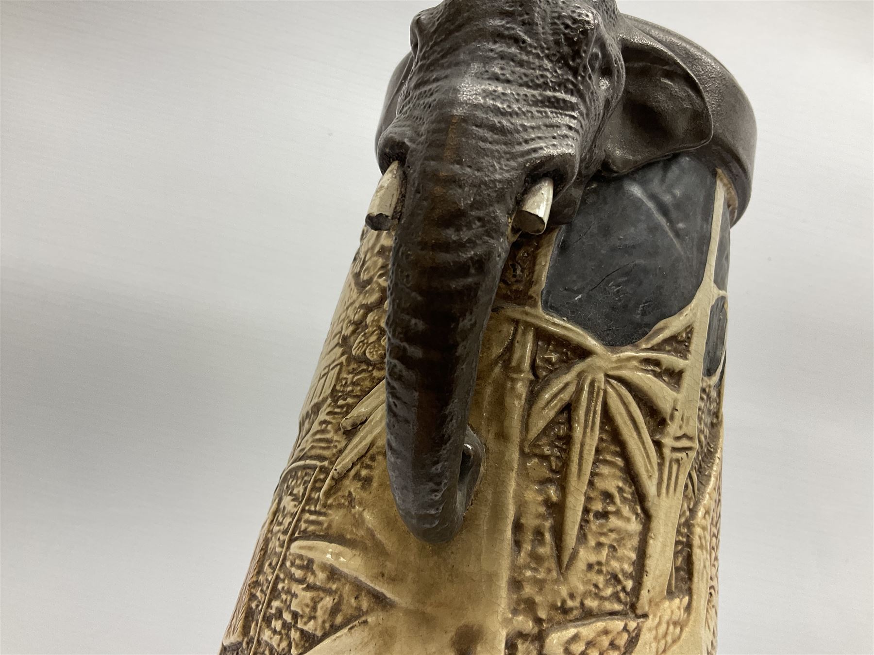 Pair of Bretby vases of tapering cylindrical form decorated with elephants, cranes and fishermen, the bodies with twin elephant mask handles, with coppered borders, raised upon three bun feet, stamped Bretby 2246 marks beneath, H32cm