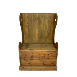 Waxed pine hall settle bench, high wing back with pierced and shaped end supports, hinged box seat, on plinth base