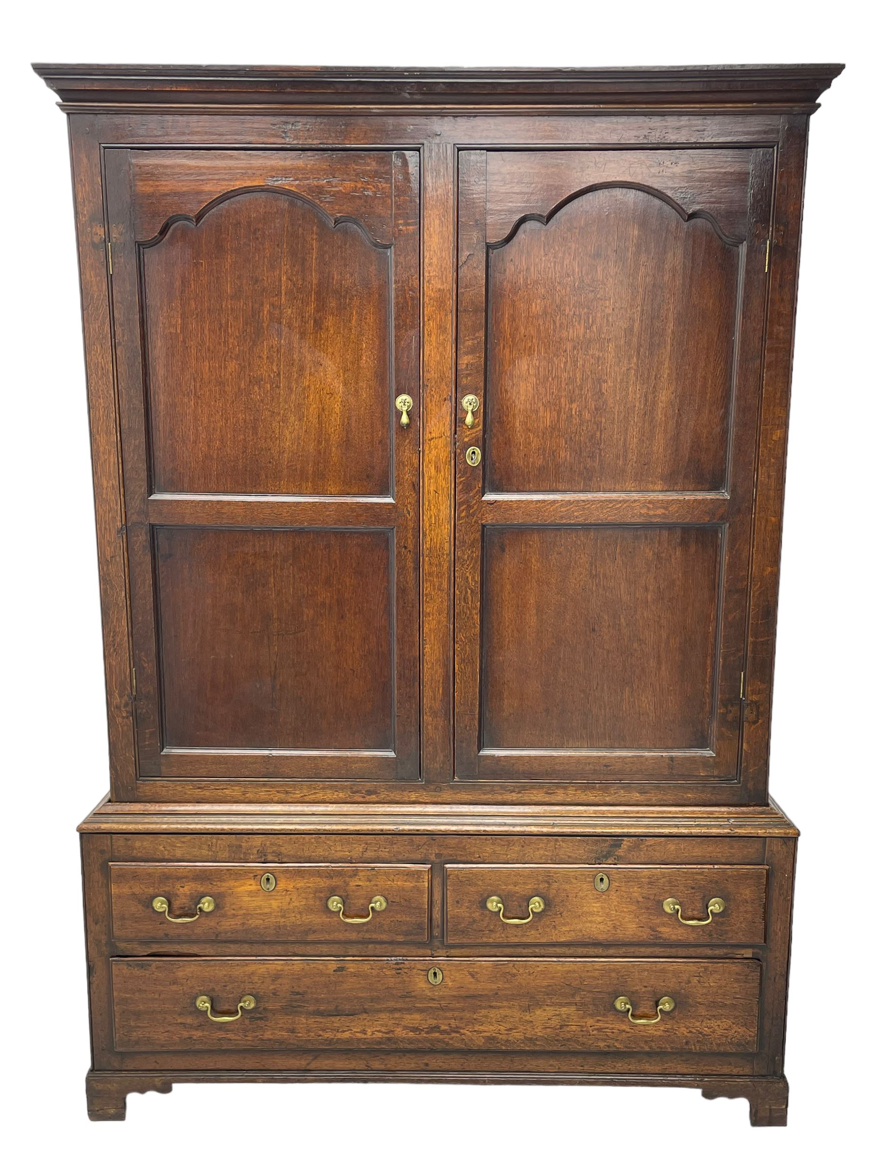 George III oak livery cupboard, projecting moulded cornice over two panelled doors, the upper panels within stepped ogee and arched moulded frame, the interior fitted with a single row of wooden hooks, two short and one long drawers, on bracket and return skirted base 