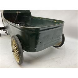 Mid 20th century pressed steel pedal car, the body painted in dark green fitted with pretend radiator to the bonnet, with spoked wheels and rubber tyres, the interior with pedals and steering wheel, L70cm