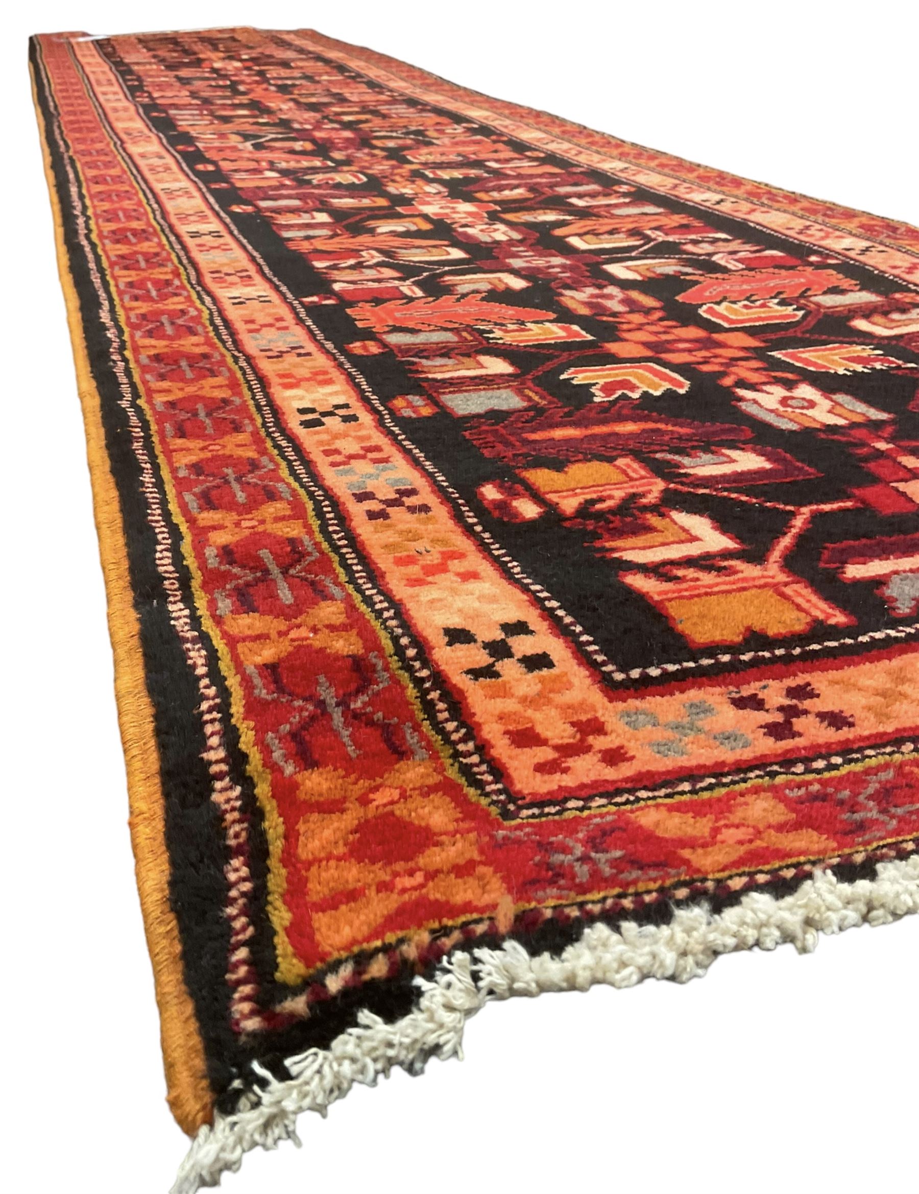 North West Persian Heriz runner, dark indigo ground field decorated with Herati motifs, peach and red borders with geometric design 