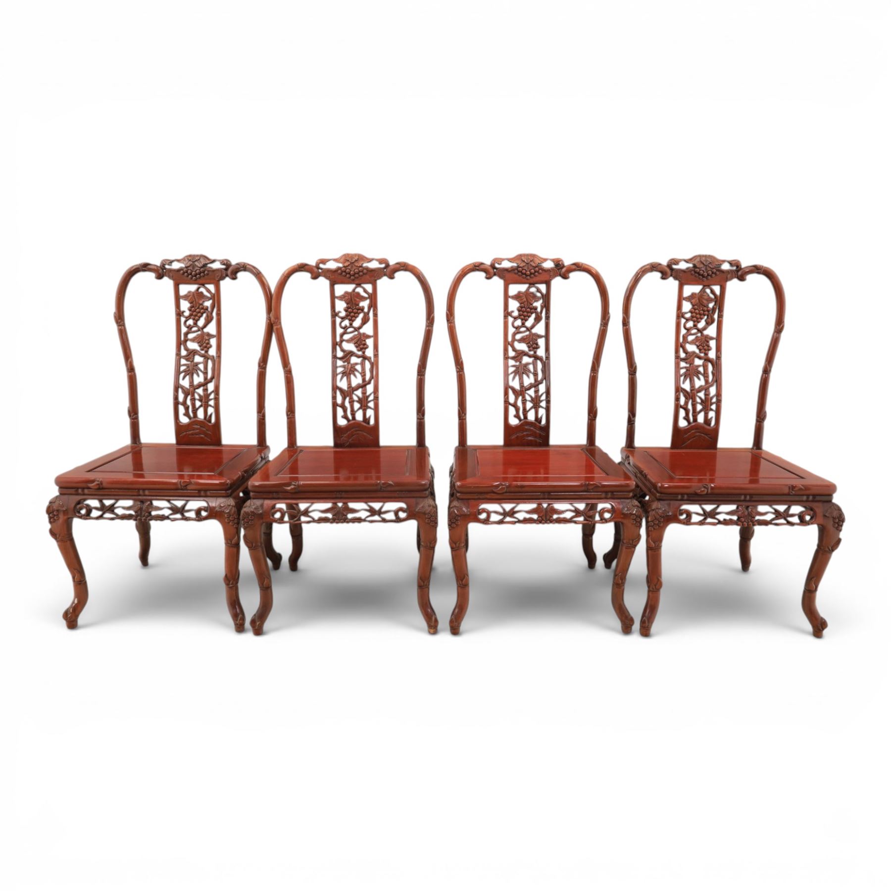 20th century Chinese ornately hardwood dining table and chairs, circular table with 'Lazy Susan' top with pierced carved frieze, raised on a quadriform base with carved foliate detail, the chairs en suite with carved pierced detailing  