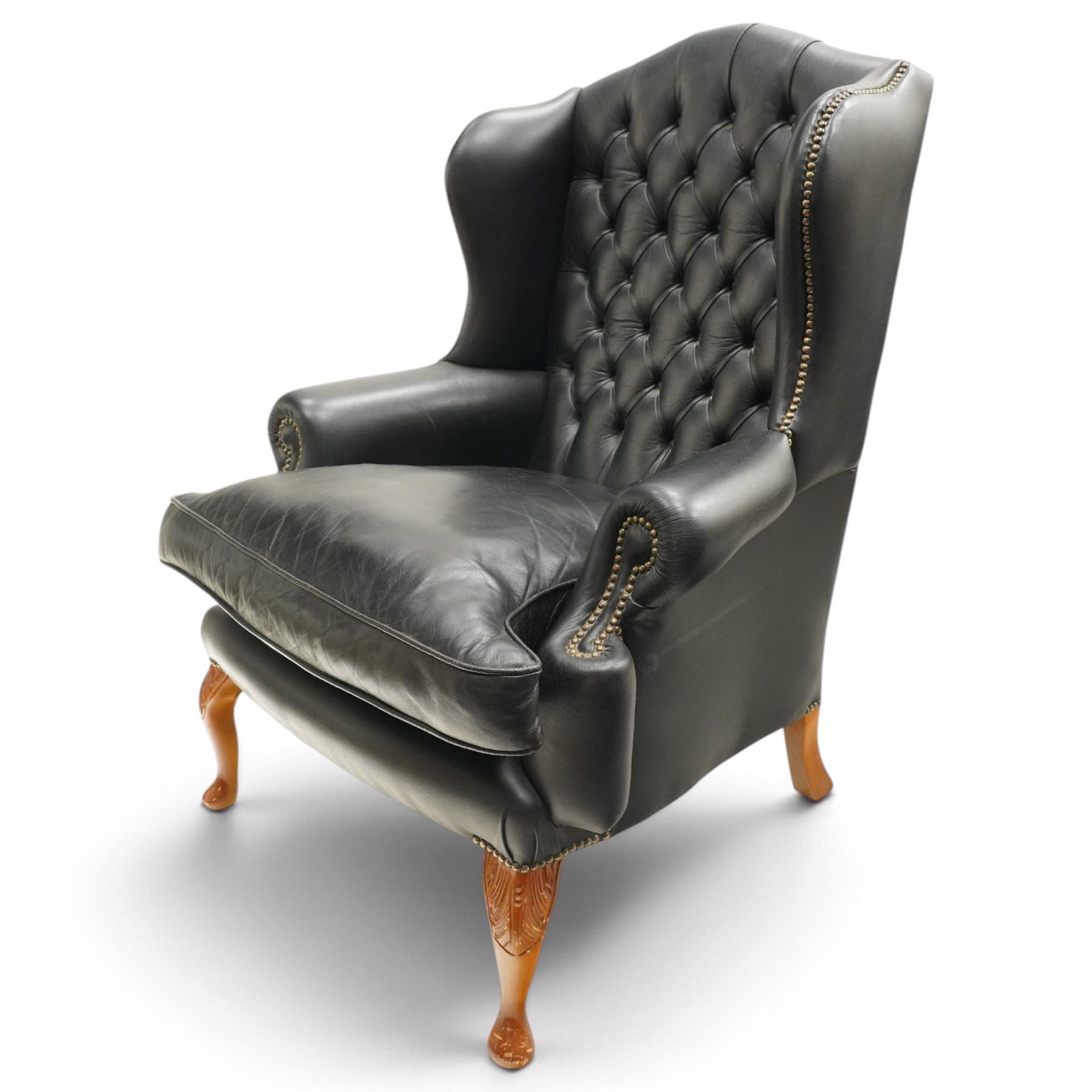 Pair of quality Georgian design wingback club armchairs, the high arched back with wings over rolled arms, upholstered in back-buttoned black leather with loose seat cushion, raised on foliate carved cabriole supports