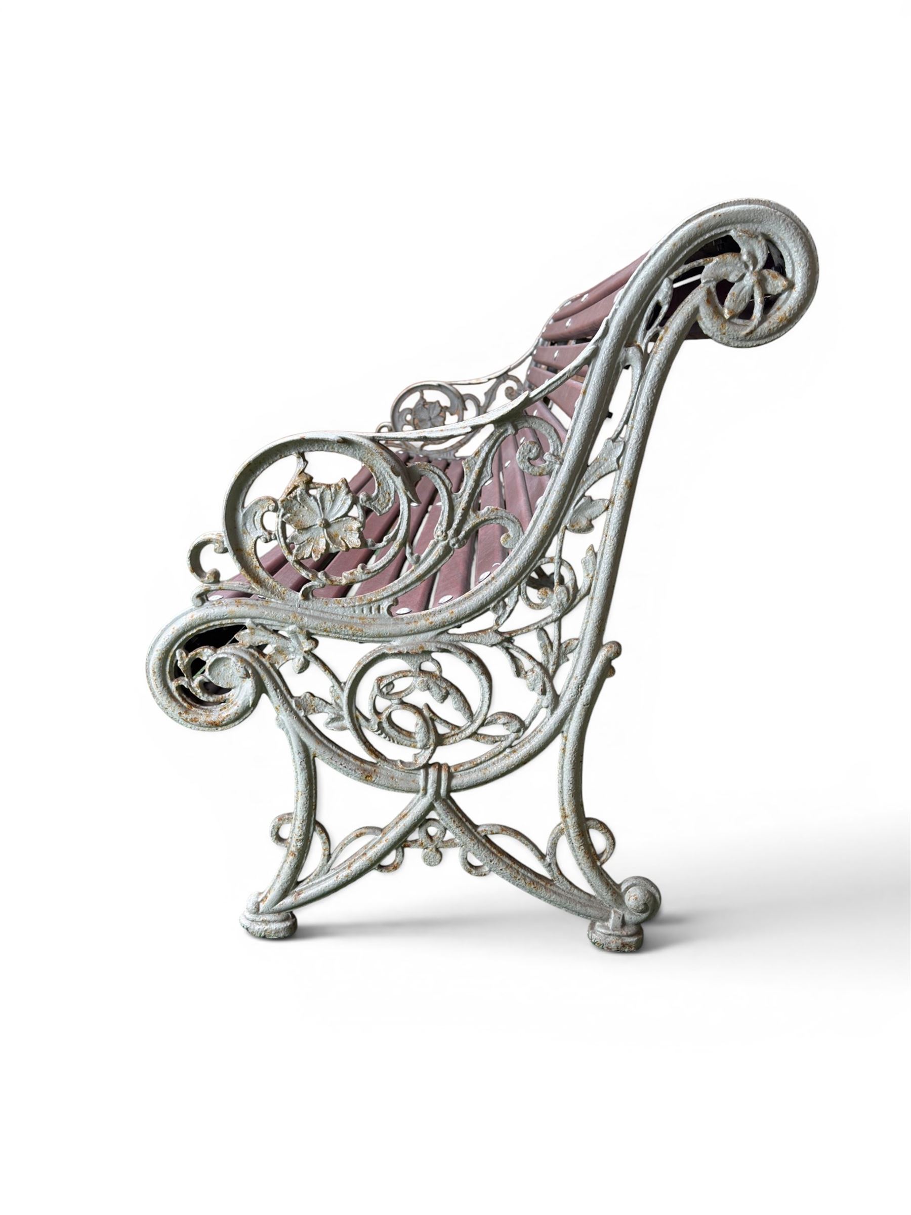 Large late Victorian cast iron garden bench, serpentine form with scroll back and seat, slatted with mahogany stained Sapele