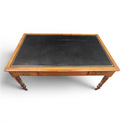 Victorian pitch pine writing table with leather inset top, rectangular top with three frieze drawers, pierced brass handles, raised on turned and fluted supports terminating in castors