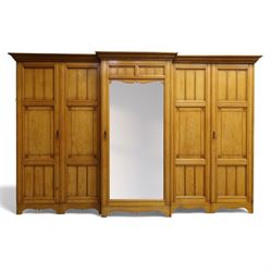 Gothic revival ash breakfront wardrobe in the manner of Charles Bevan, the four fielded panelled doors flanking a central mirrored door, opening to reveal an fitted interior with hanging rails and compartment shelves and drawers, upon a shaped plinth base with bracket cut feet

