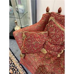 Large Knole design hardwood-framed three-seat drop-arm sofa, upholstered in crimson fabric decorated with trailing acanthus leaves and shields, together with scatter cushions 
