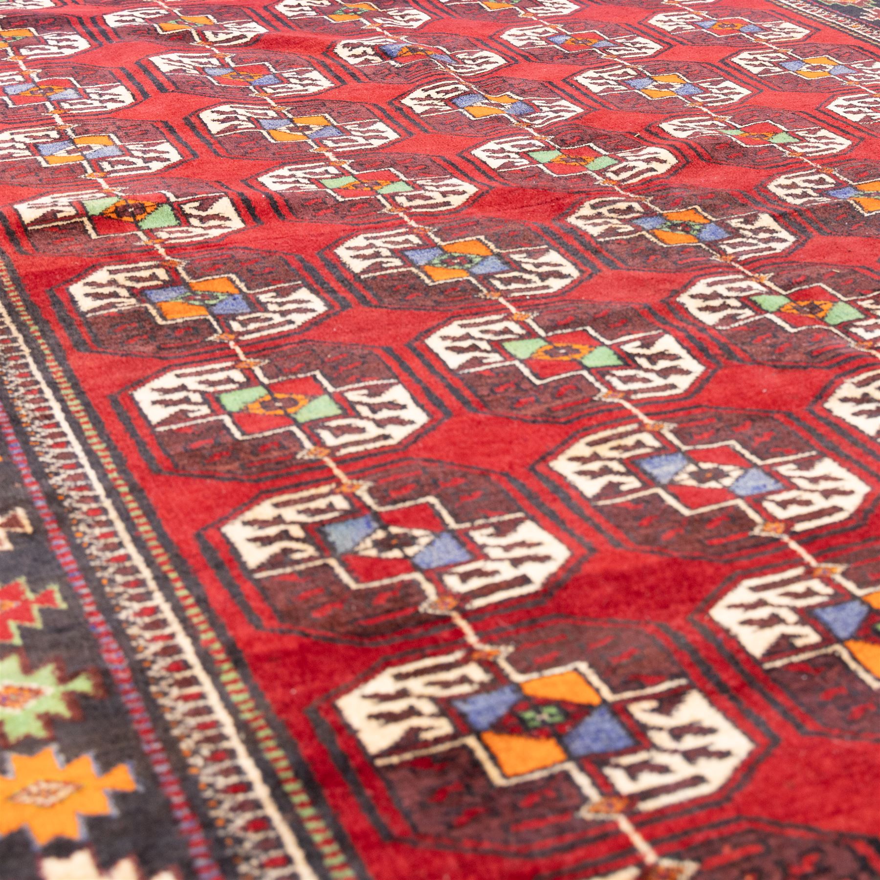 Tekke Bohara hand-knotted rug, madder red field decorated with an all-over design of repeating octagonal guls and latch-hook motifs within multiple geometric borders and cotton fringe ends 