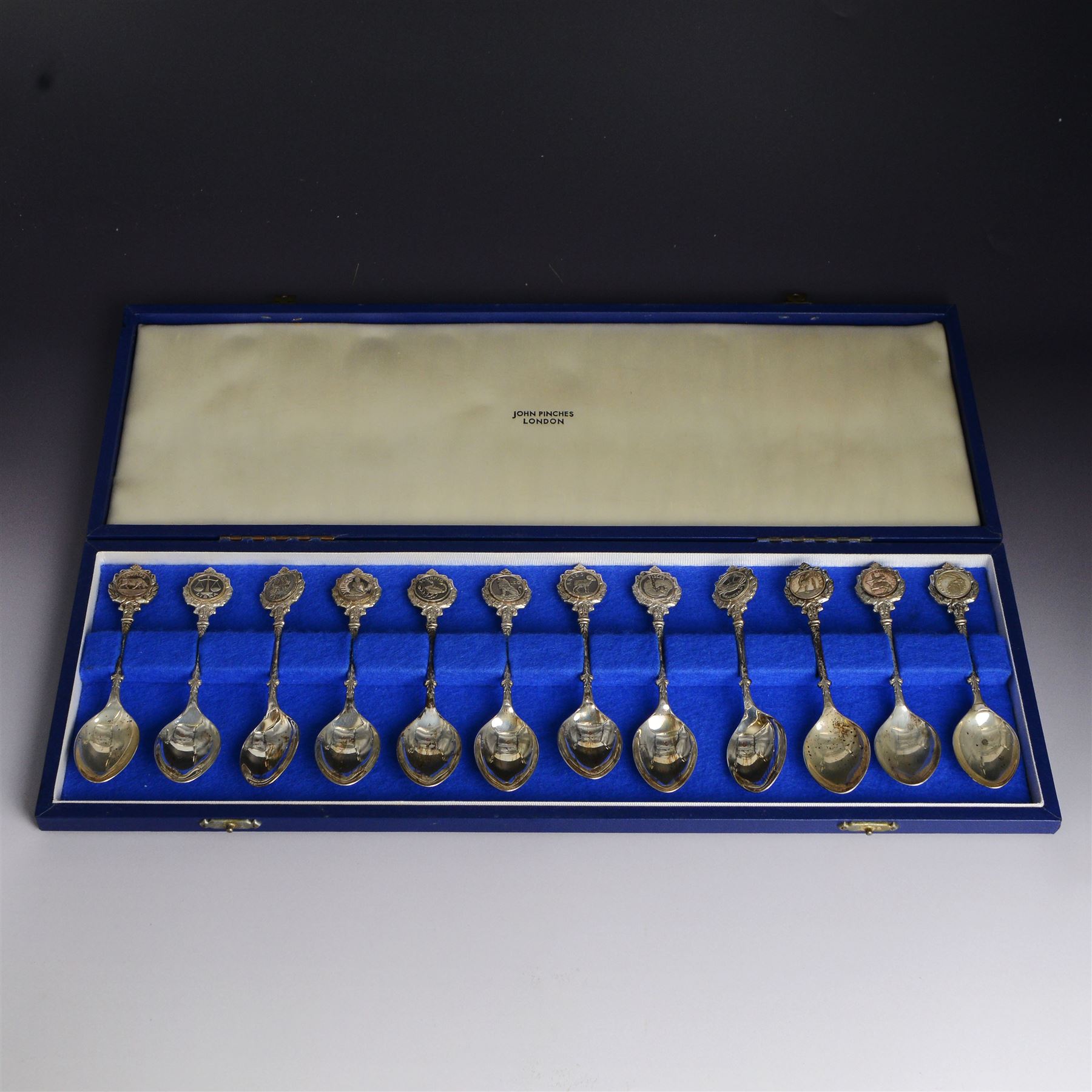 Set of twelve modern silver teaspoons 'The Twelve Zodiac Spoons', all decorated with symbols of the zodiac, hallmarked John Pinches, London 1971, contained within fitted case