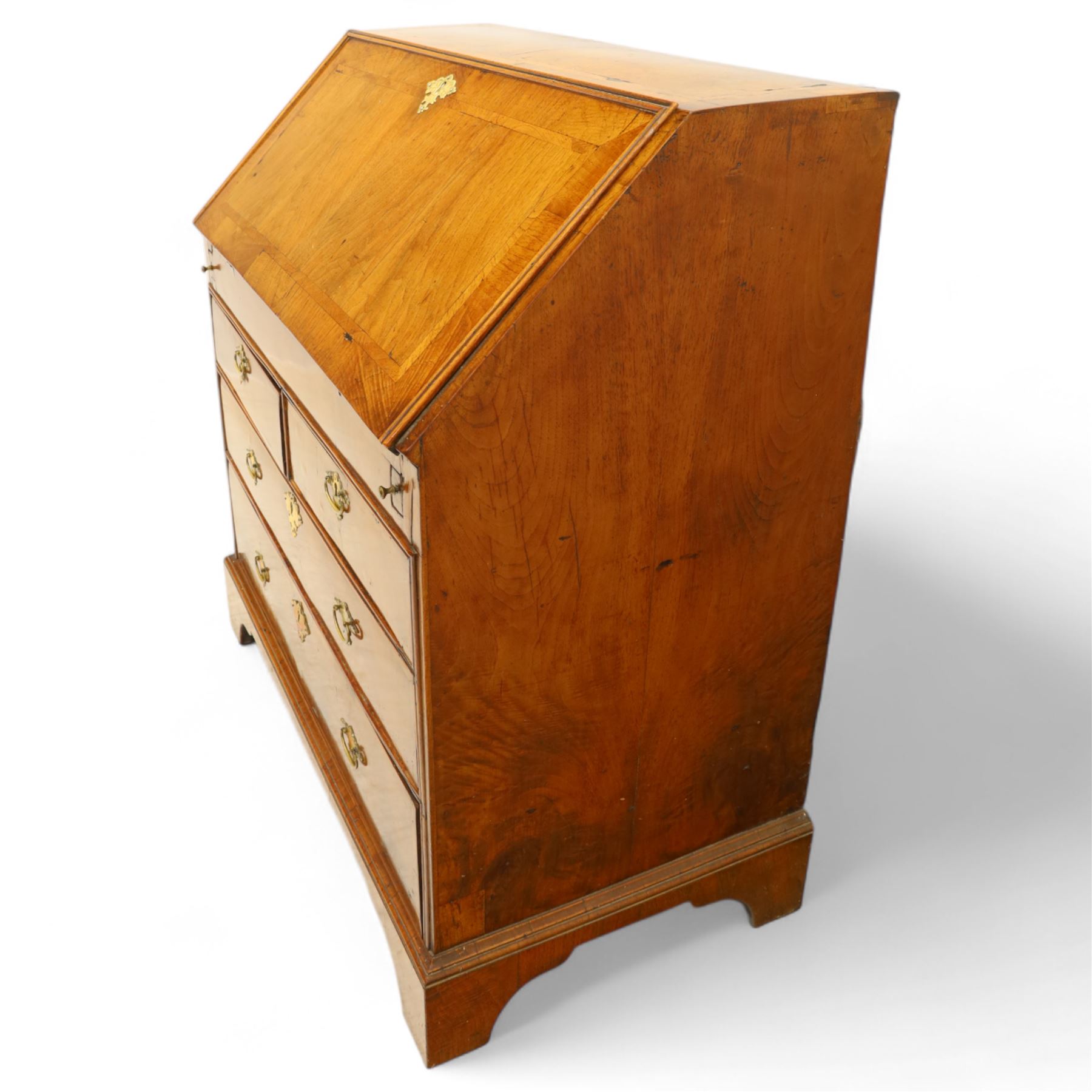 18th century walnut and herringbone banded bureau, the fall front enclosing a stepped and arched interior fitted with pigeonholes, drawers and concealed compartments, green tooled leather writing surface, over two short and three long graduated drawers with brass escutcheons and bail handles, shaped bracket feet