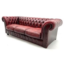 Three seat chesterfield sofa upholstered in deep buttoned ox blood studded leather, scrolling arms