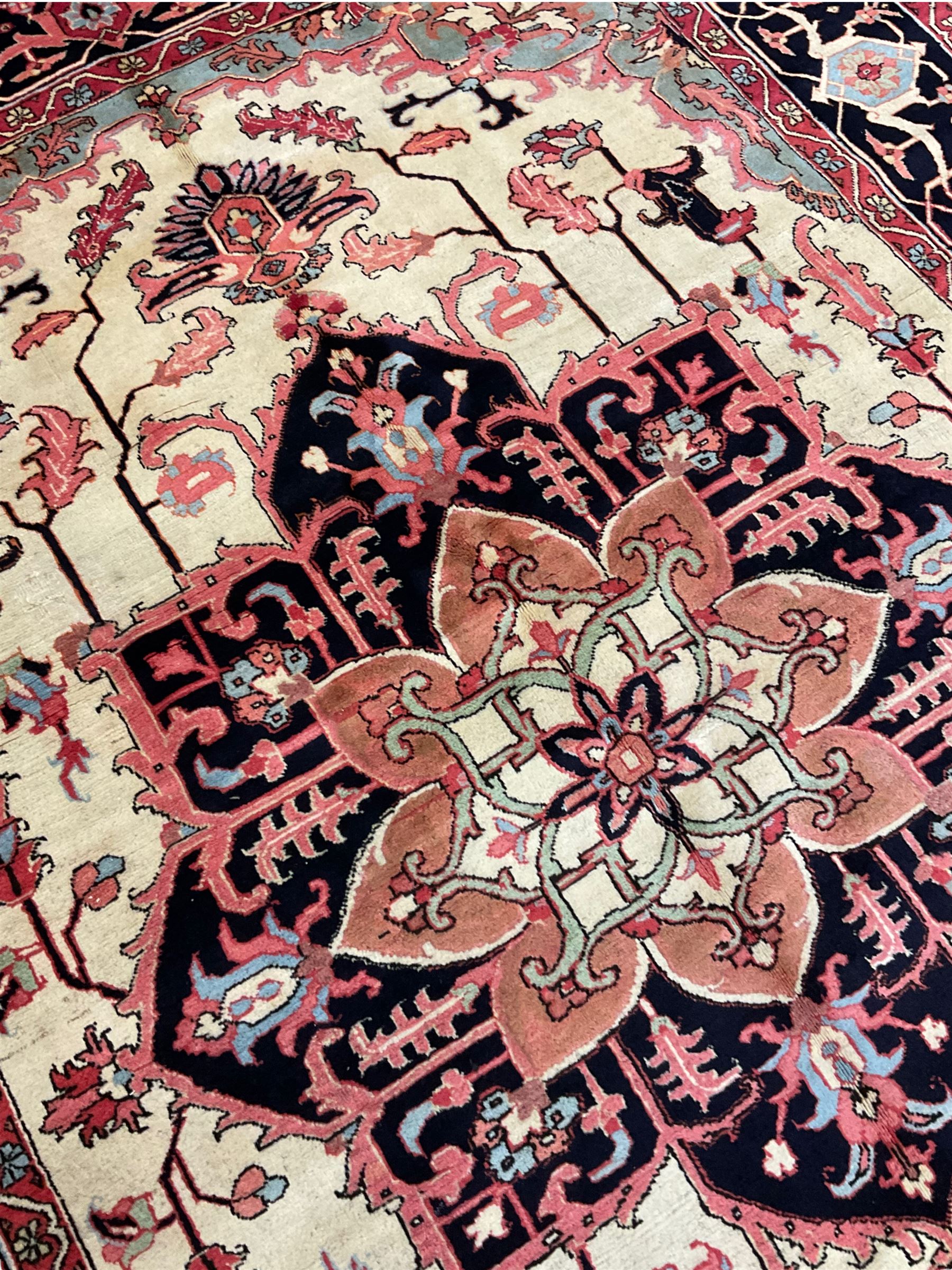 North West Persian Heriz carpet, ivory ground with large central medallion and floral spandrels, triple band border with scrolling design decorated with flower head and plant motifs 