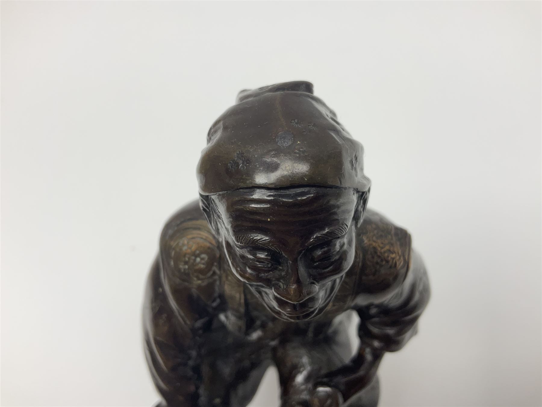 Oriental bronze figure of a gentleman, modelled seated upon barrel with a pipe in one hand and a flask in the other, H21cm