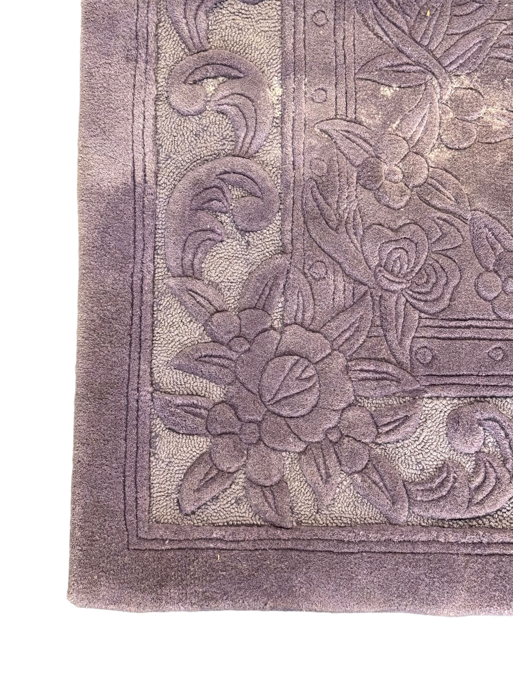 Chinese wool rug, purple ground with tonal floral and foliate pattern, central medallion of stylised flowers, the corners with large rosettes, framed by broad border of scrolling floral and leafy motifs 