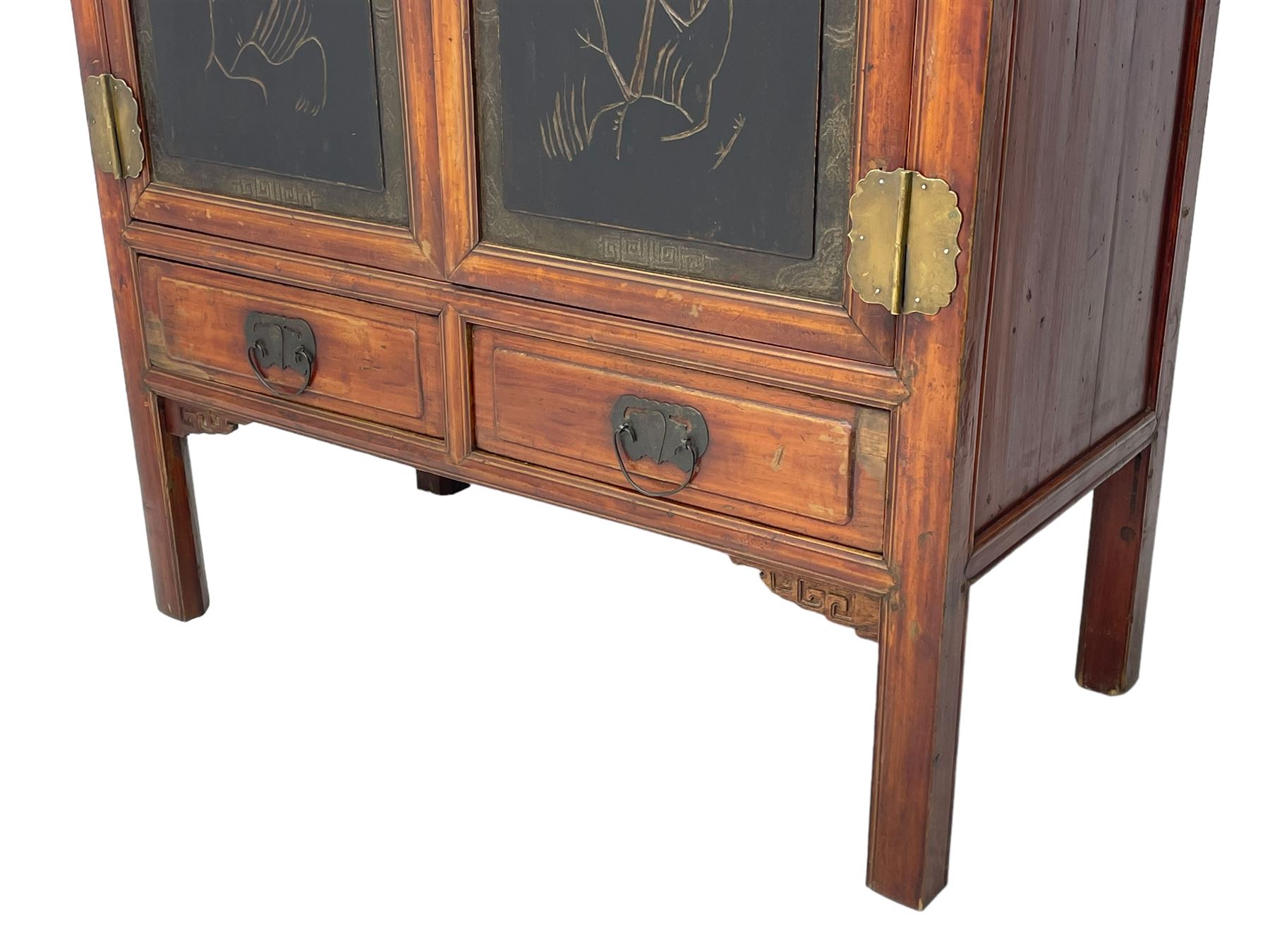Late 19th century Chinese Qing dynasty red and black lacquered wood cabinet,  Fujianese province, upper cupboard enclosed by two doors with relief carved and gilt panels depicting figures behind glass, the large cupboard enclosed by two panelled doors carved with trailing foliate branches and birds, inscribed with Chinese characters, to the left ‘The red mountains are in the shape of Phoenixes and appear auspicious’ and to the right, ‘Wealth and honour are given by flowers and I hear the sound of the phoenix', fitted with two drawers, on square supports with carved brackets 