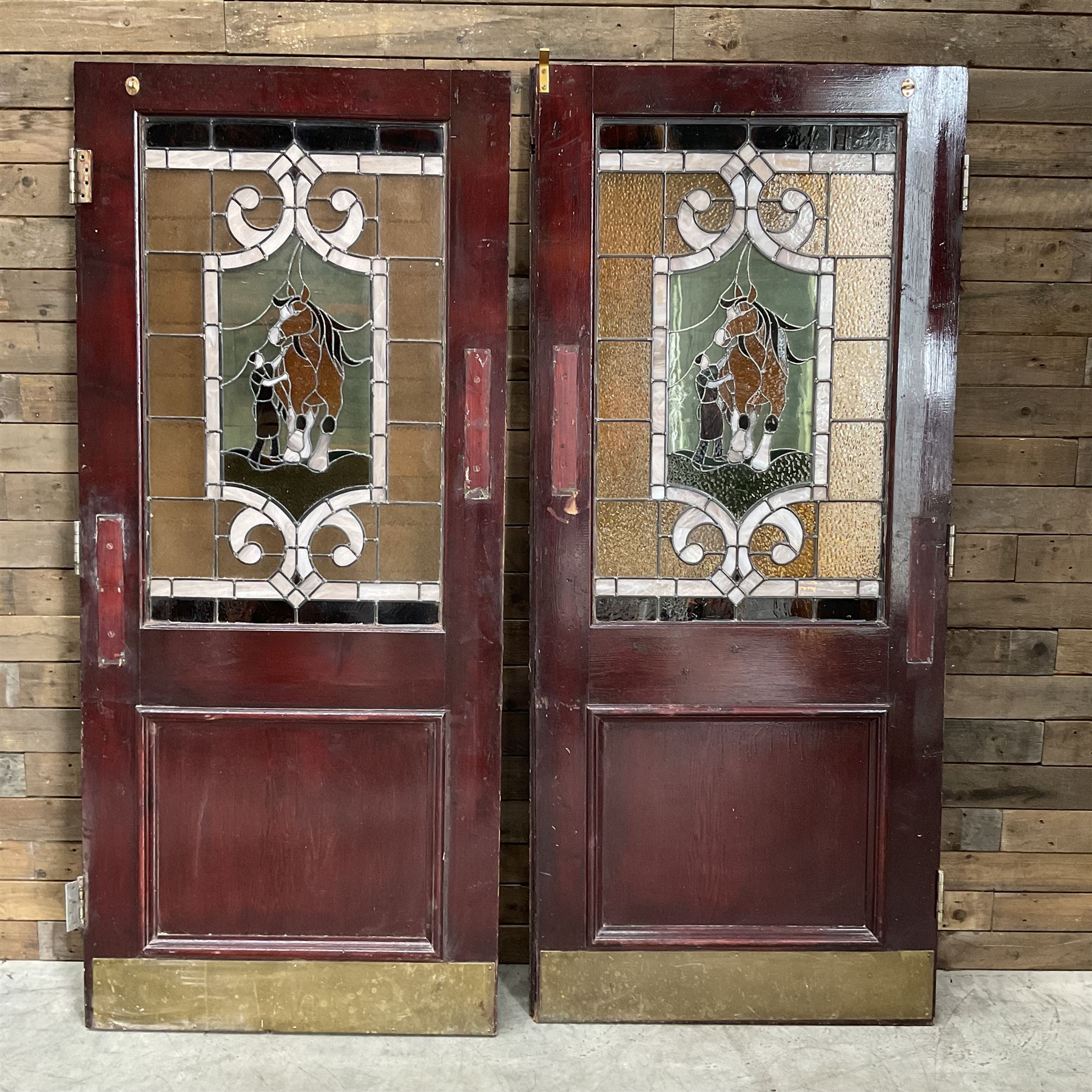 Two early to mid 20th century timber doors, set with lead framed stained glass panels depicting agricultural worker and horse