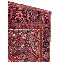 Antique Persian coral ground carpet, the large central floral pole medallion with extending foliate designs, the thick guarded indigo border with repeating flower heads and circles