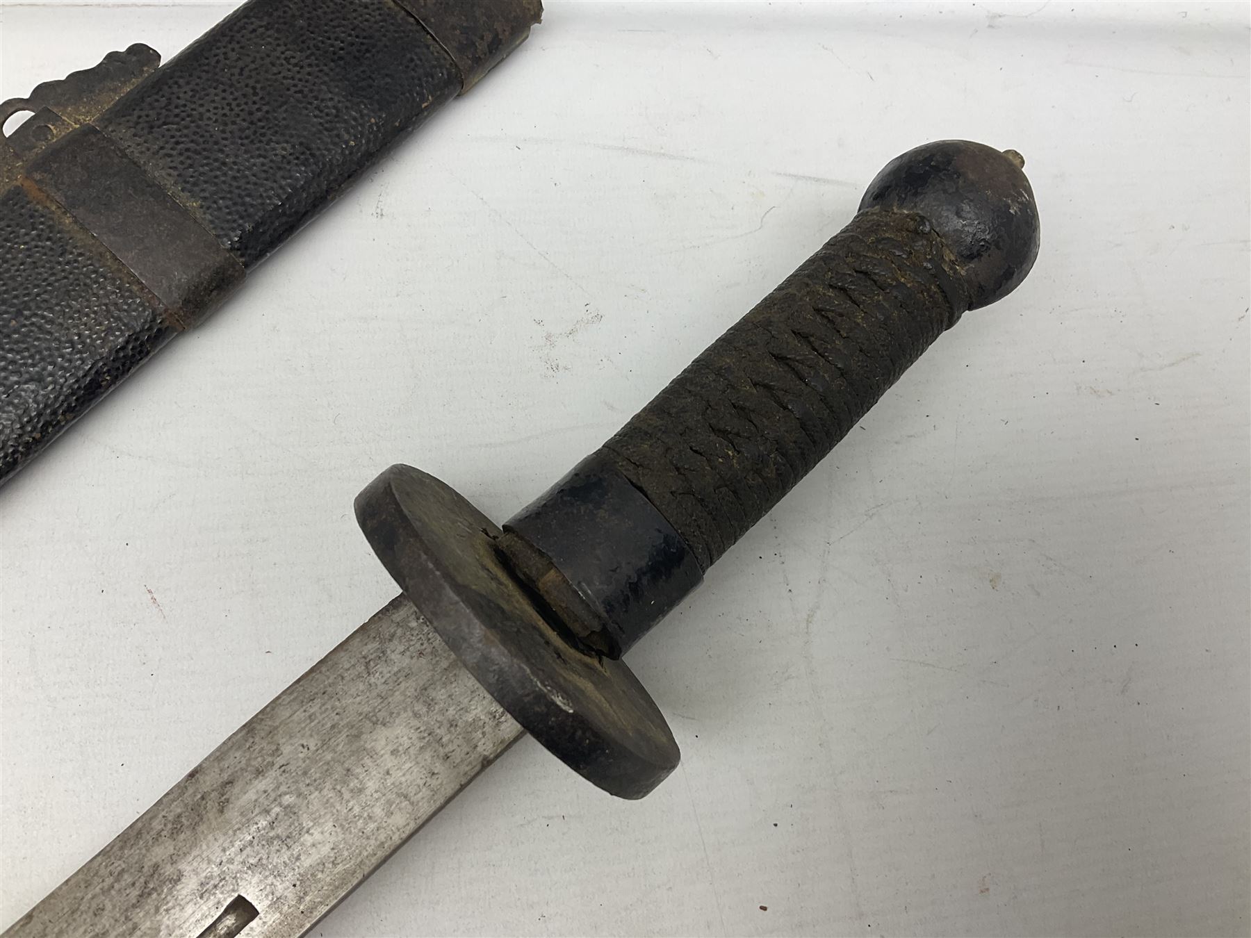 Chinese Boxer Rebellion Period Sword, 69.5cm heavy curved single edge blade with single narrow fuller, plain iron dished circular guard, iron pommel and ferrule with plaited cord bound grip; in skin covered wooden scabbard with iron chape and long suspension mount L95cm overall