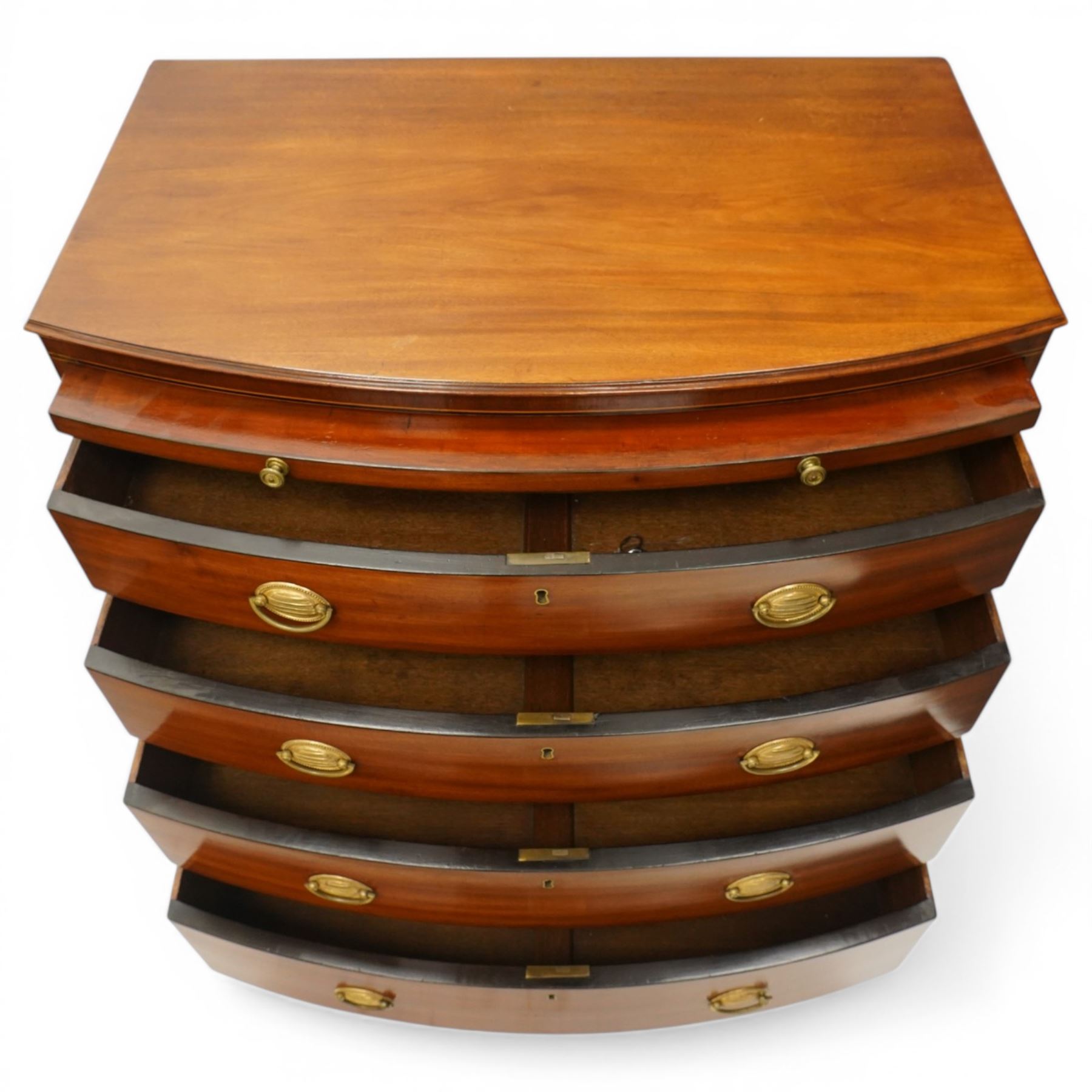 Regency period mahogany bow-front bachelor's chest, shaped top with moulded edge, fitted with brushing slide over four long graduating drawers, each with original pressed brass handle plates, raised on splayed feet 