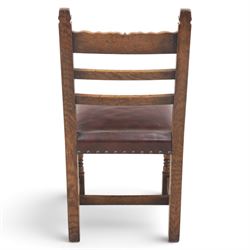 Craftsman made set of four solid oak dining chairs with leather seats, with carved cresting rail, on red leather seats with studded trim, raised on block and turn supports united by H-stretcher