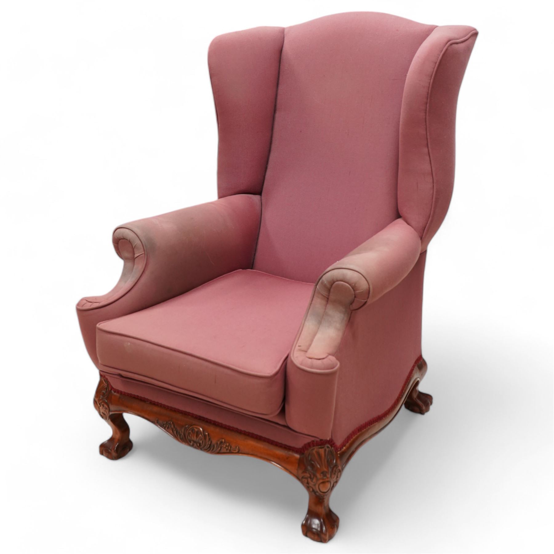 Georgian design mahogany framed wingback armchair, upholstered in rouge fabric, on ball and claw feet with foliate cartouche decoration 