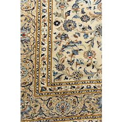 Central Persian Kashan hand-knotted rug, ivory field intricately decorated with an all-over design of scrolling vines, palmettes, and stylized lotus motifs in shades of soft blue, pale gold, and indigo within floral borders