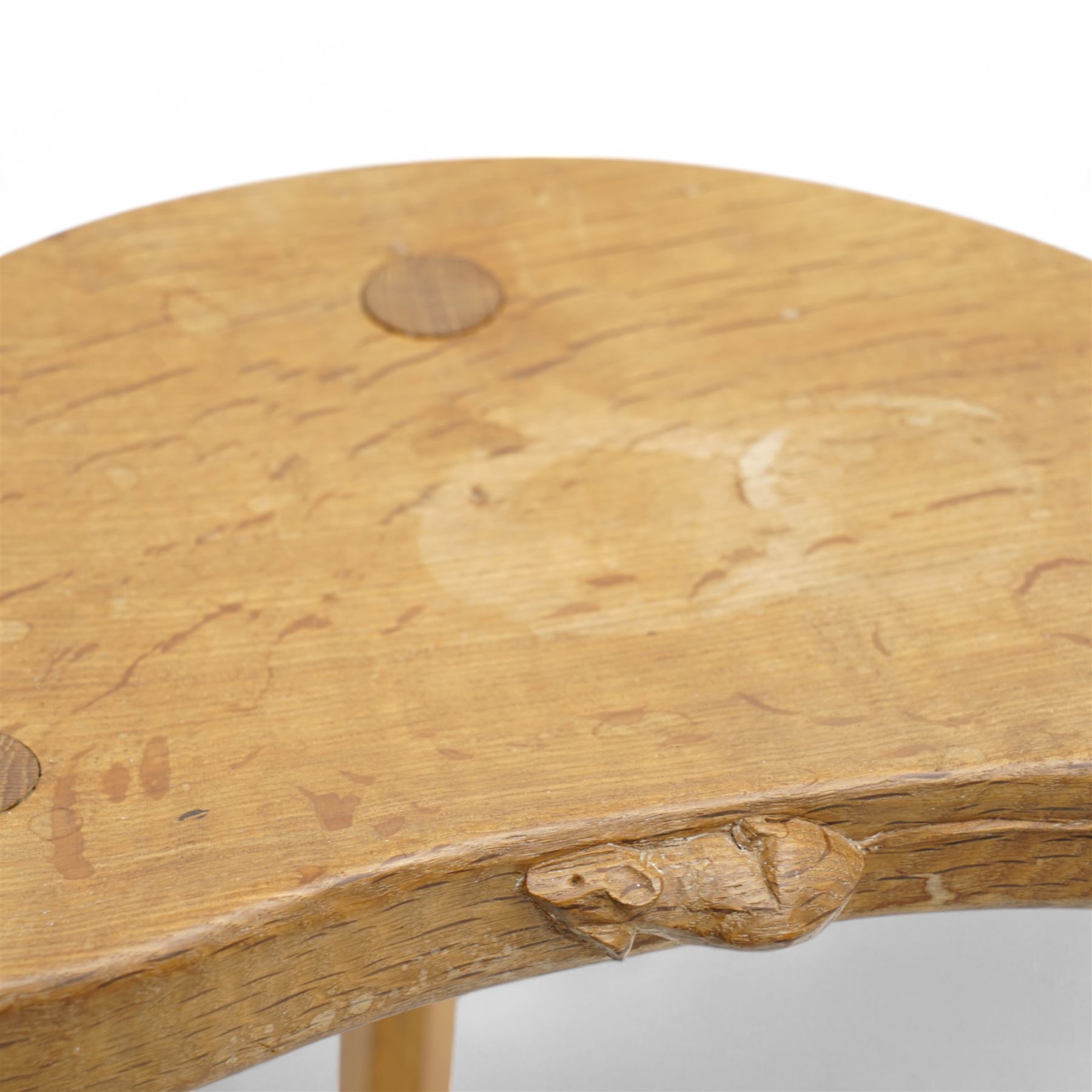 Mouseman - oak three-legged milking stool, dished kidney-shaped seat carved with mouse signature, on three octagonal tapered supports, by the workshop of Robert Thompson, Kilburn