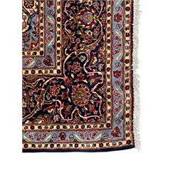 Persian Kashan indigo ground carpet, central floral pattern medallion surrounded by a densely decorated field depicting trailing branches with leaves and palmettes, scrolling border decorated with stylised plant motifs, within floral pattern guard stripes 