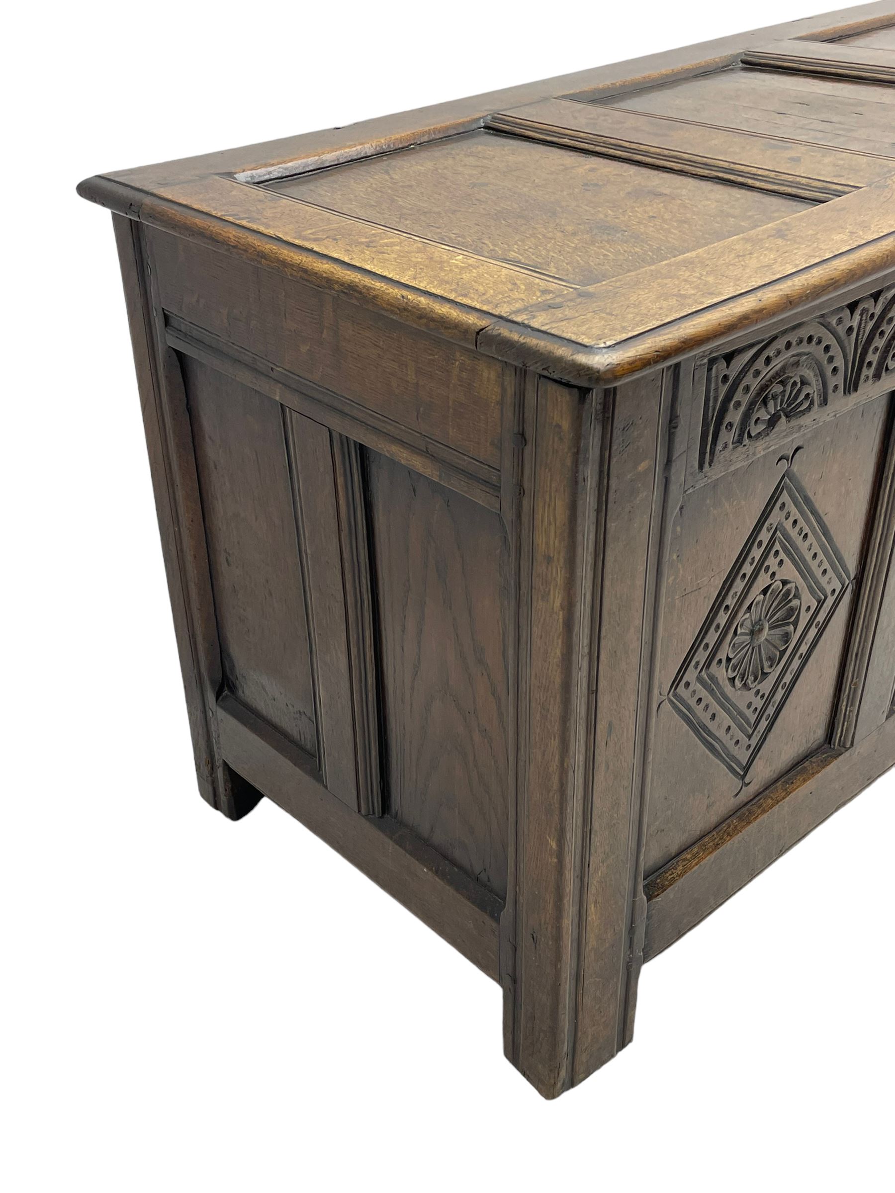 18th century oak coffer or chest, rectangular triple panelled hinged top with moulded edge enclosing main compartment and candle box, the frieze carved with repeating concentric lunettes and foliate patterns, the front fielded panels decorated with lozenges containing central flower heads, on stile supports