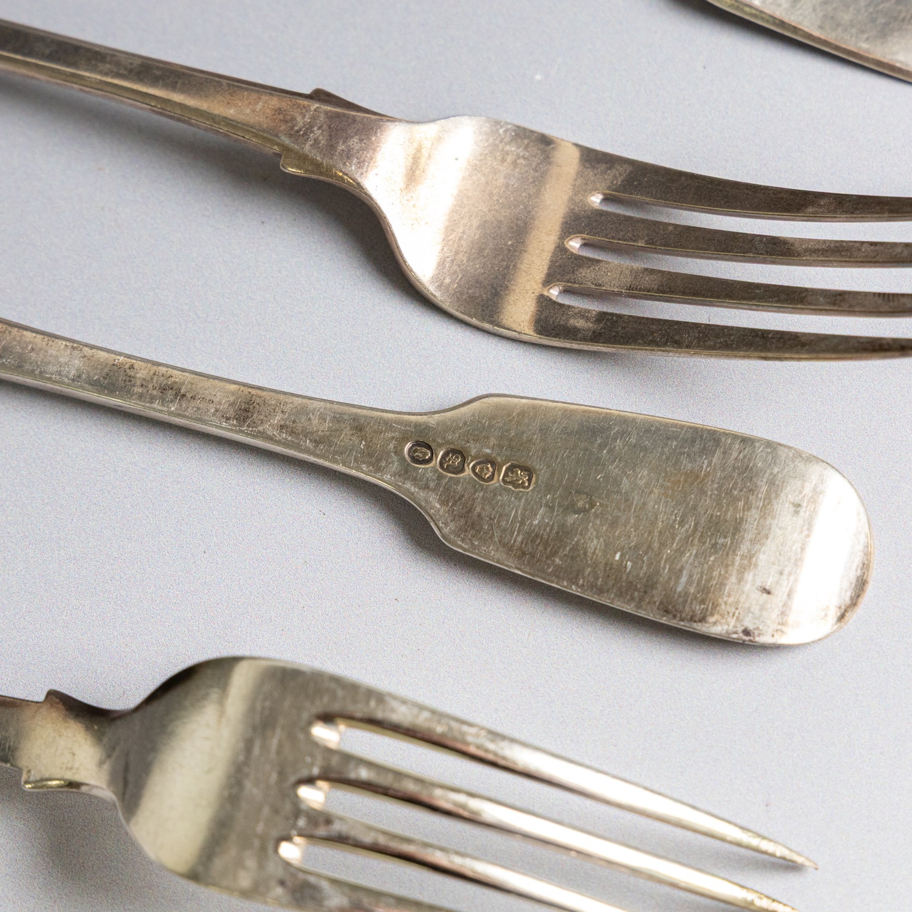 Seven silver Fiddle pattern table forks, comprisng set of four William IV examples, hallmarked William Eaton, London 1836, and three Victorian examples with engraved initials, hallmarked John Robert Harris, London 1846