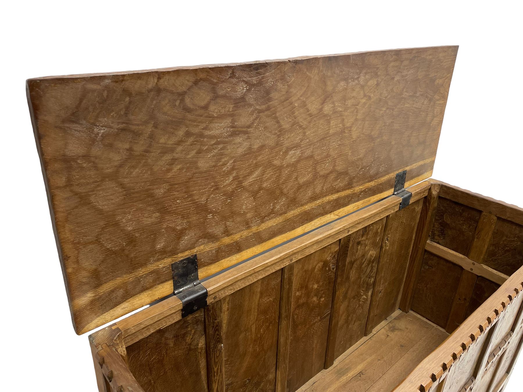 Gnomeman - oak blanket box, all-over adzing, the hinged top over figured and burr panelled front, decorated with carved crenellations and arcade, carved with gnome signature, pierced handles to each end forming the central rail, wrought metal hinges, on stile supports, by Tom Whittaker, Littlebeck, Whitby