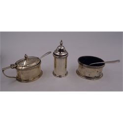 Early 20th century silver three piece cruet set, comprising mustard pot and cover, open salt and pepper shaker, each of faceted form, with foliate rim, the mustard pot with angular handle and the pepper shaker with urn finial, hallmarked Manoah Rhodes & Sons Ltd, London 1928, mustard pot and salt with blue glass liners, together with two matched silver plated condiment spoons, all contained within fitted case