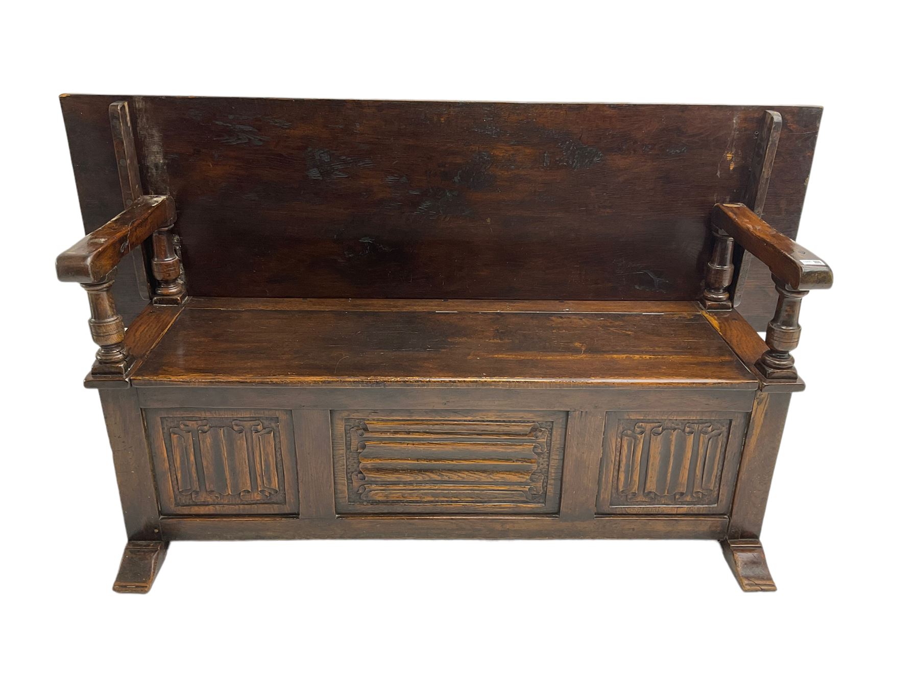 Jacobean design oak Monks bench, the front with carved linenfold panels, hinged metaphoric table back, hinged box seat compartment, on sledge feet