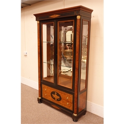  Empire style ebonised banded satinwood display cabinet with brass capped half columns enclosing two bevelled glass doors, above two drawers on bun feet, W118cm, H201cm, D40cm  