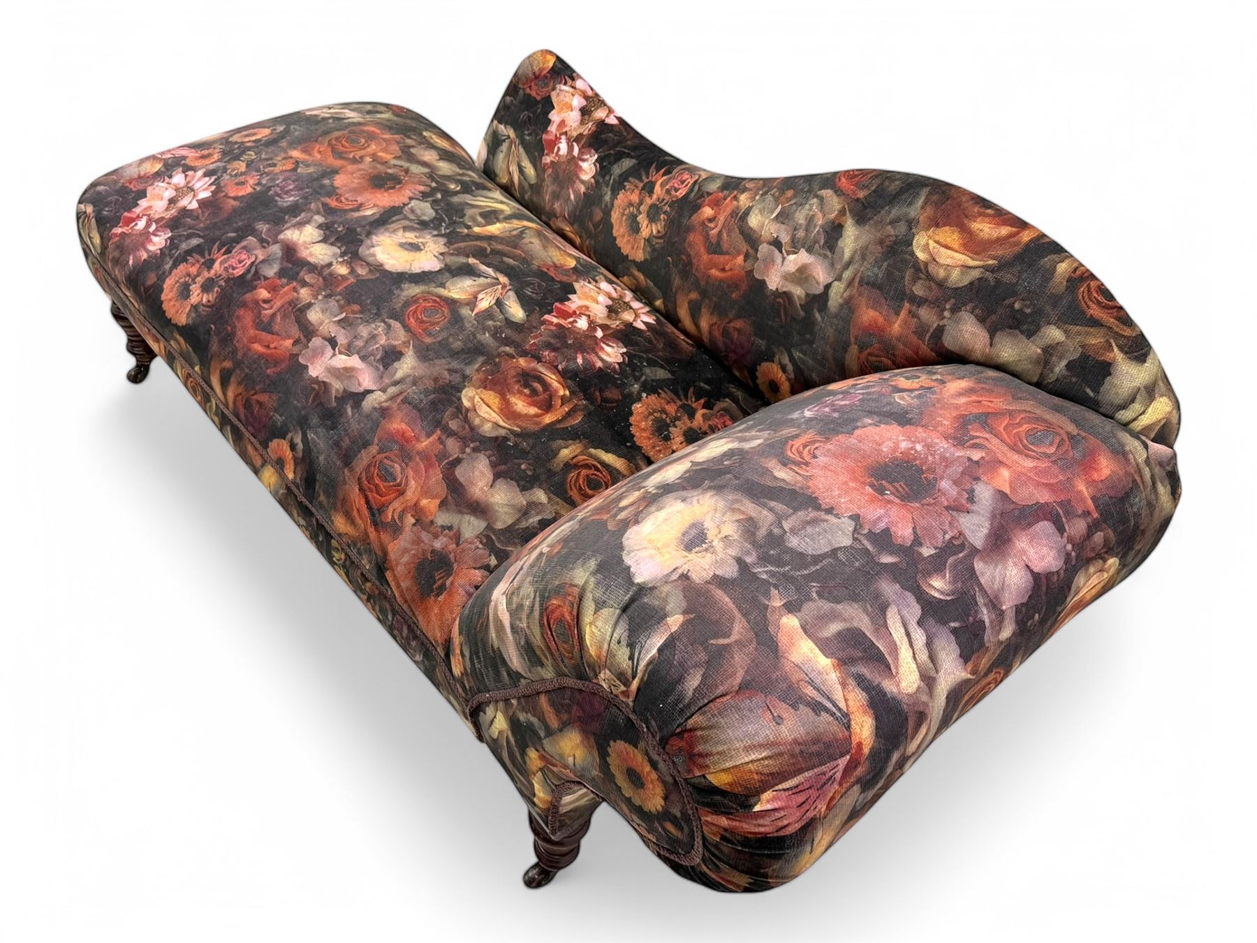 Victorian hardwood-framed chaise longue, serpentine back with rolled arm, upholstered in floral pattern fabric, on ring turned legs with ceramic castors 