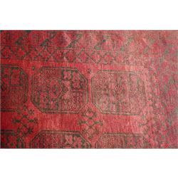 Afghan crimson ground Bokhara rug, the field with three rows of repeating Gul motifs, within six concentric guard bands decorated with repeating geometric patterns