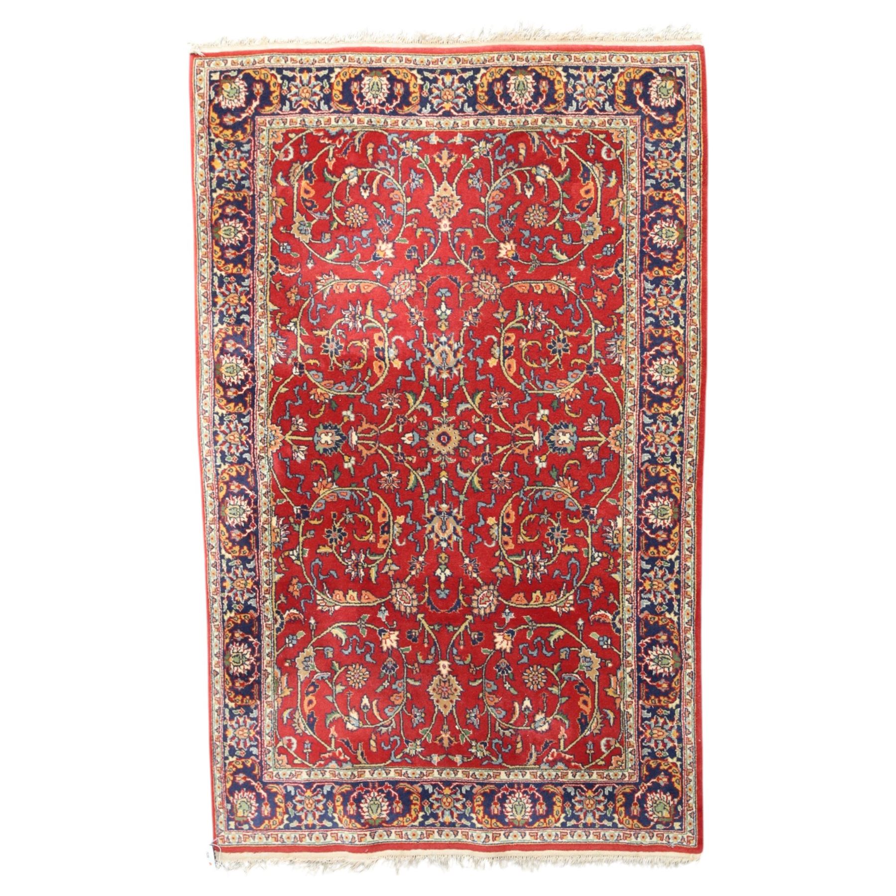 Persian Kashan crimson ground rug decorated with scrolling foliage, the indigo guard stripes with repeating stylised palmette motifs