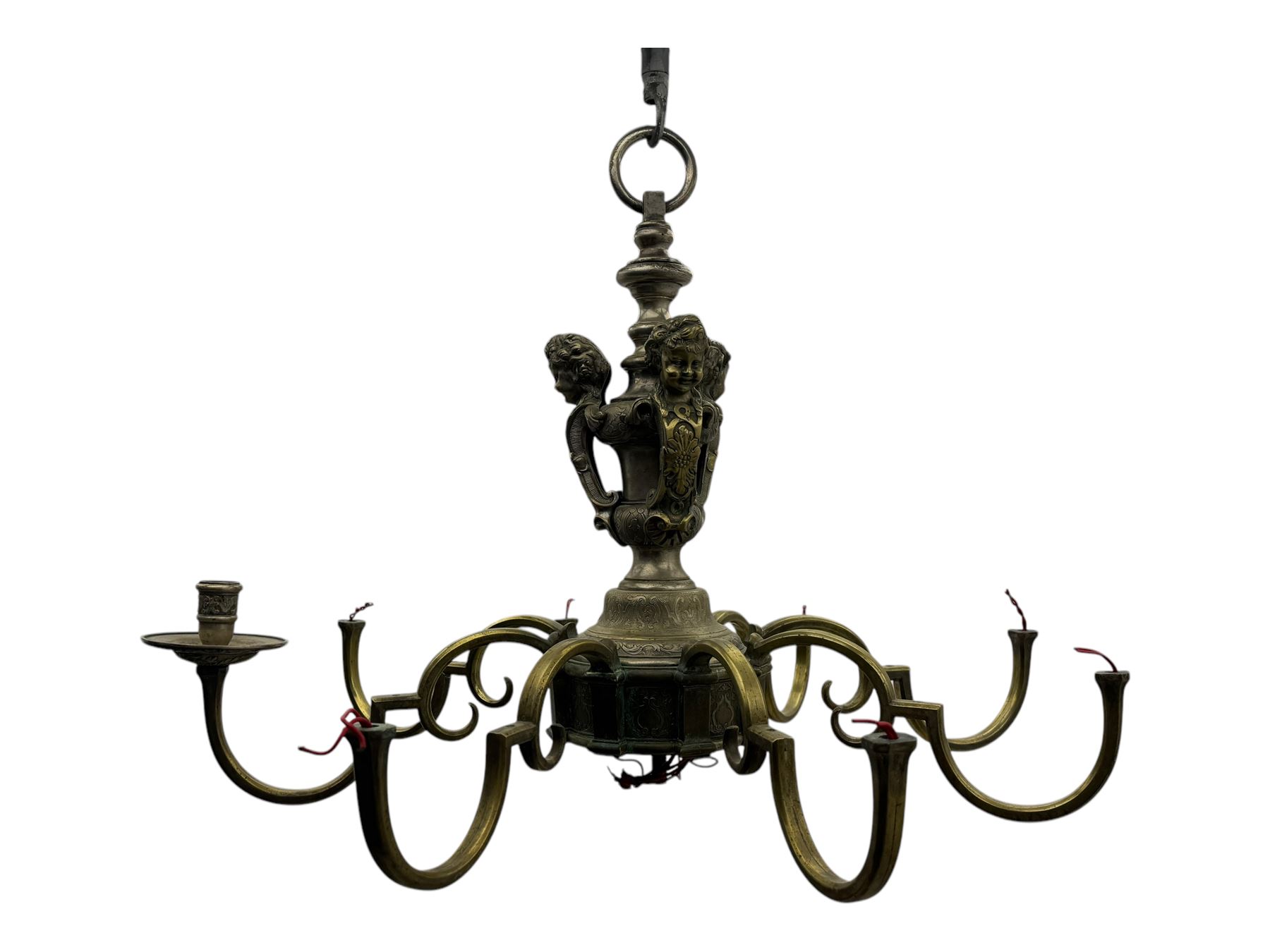 Early 20th century cast brass chandelier, the main baluster-form body surmounted by a lobed finial, with three cherubic heads and foliate scrollwork around the upper section, eight sweeping branches for lights