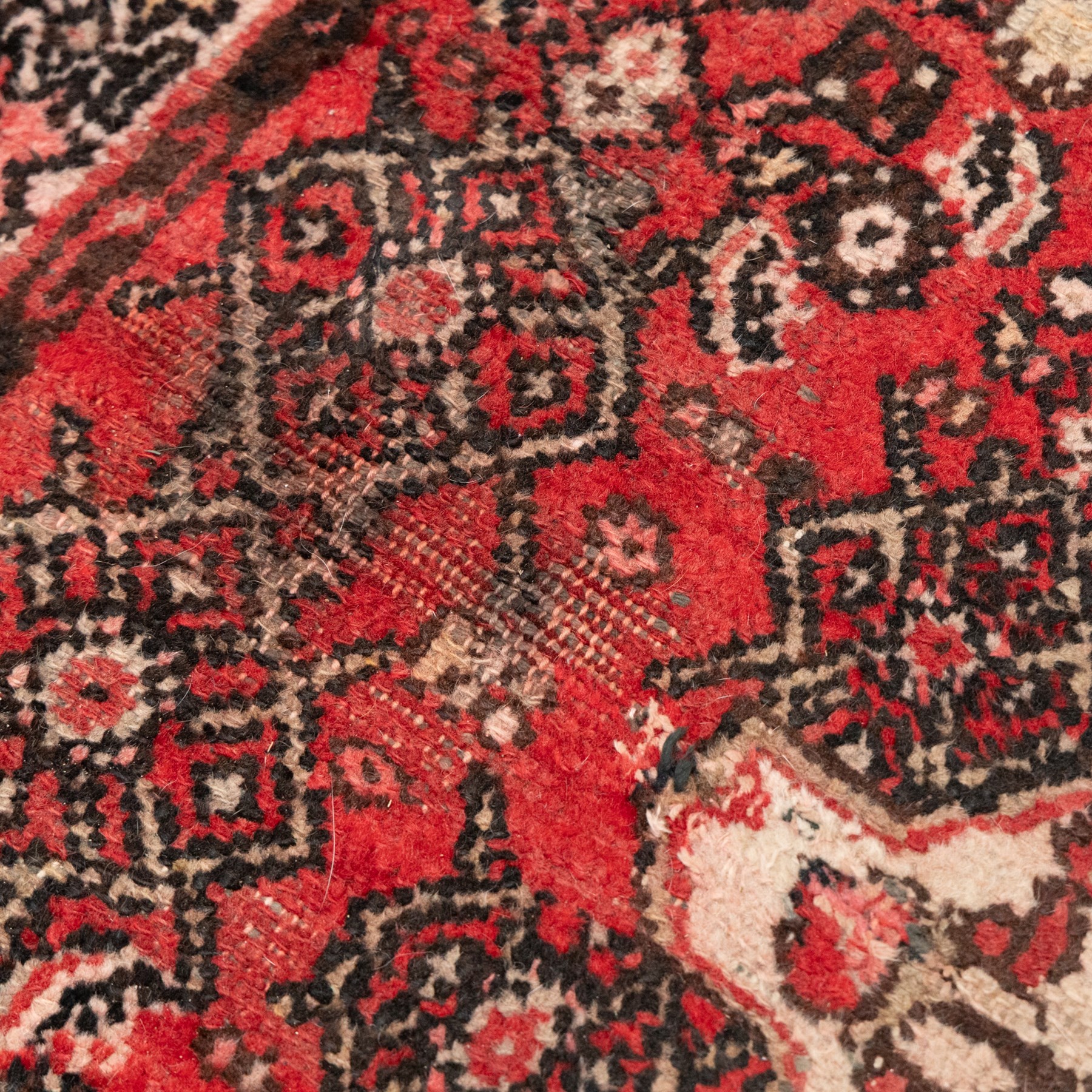 Persian crimson ground runner rug, the field decorated with repeating Herati motifs around an ivory pendant medallion, stepped ivory spandrels with stylised floral ornament, enclosed by a dark ground star border and narrow guard stripes