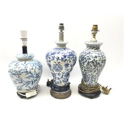 Three blue and white table lamps, each decorated with foliate pattern, and with white fabric shade, largest example overall H55.5cm.