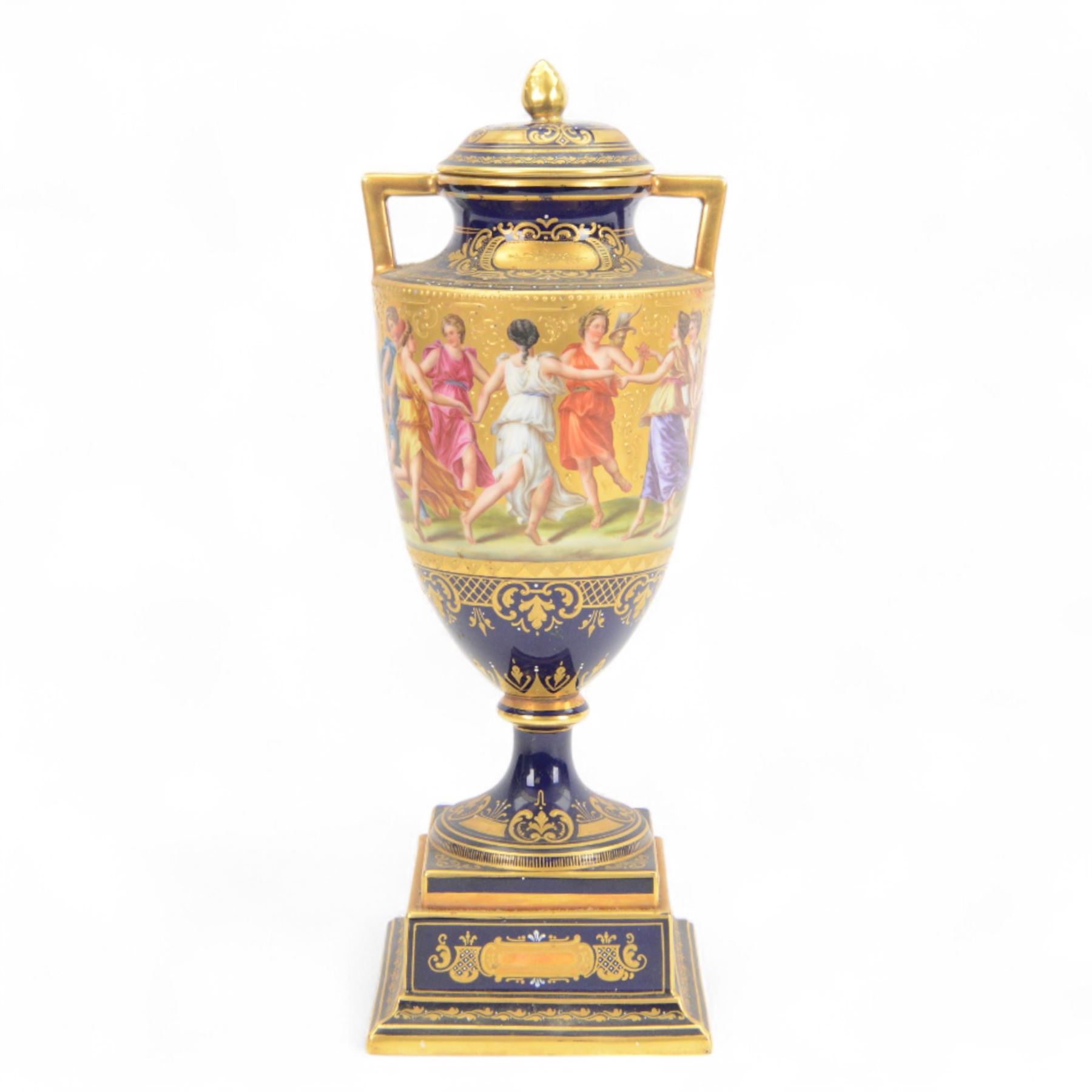 Late 19th century Vienna twin handled urn and cover decorated with classical figures on a textured gilt ground,  upon a square stepped cobalt blue pedestal with gilt detailing, H36cm